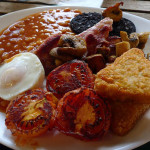 A photo of a cooked breakfast with bacon and sausages.