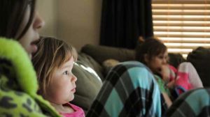 An image of a family with young children watching TV.