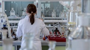 An image of a scientist working in the lab, with her back turned to the camera.