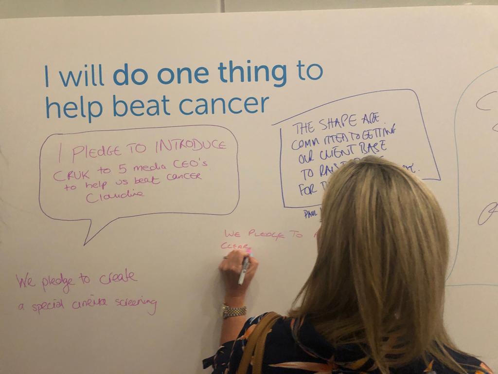 One of the guests at the Cancer Research UK Media Beats Cancer event writes a pledge on our 'do one thing' board