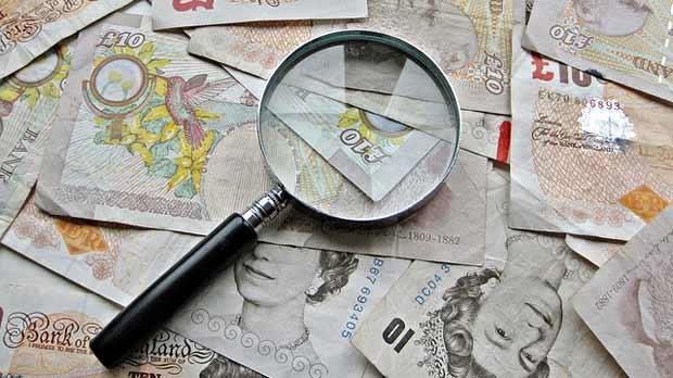 Magnifying glass sitting on pound notes.