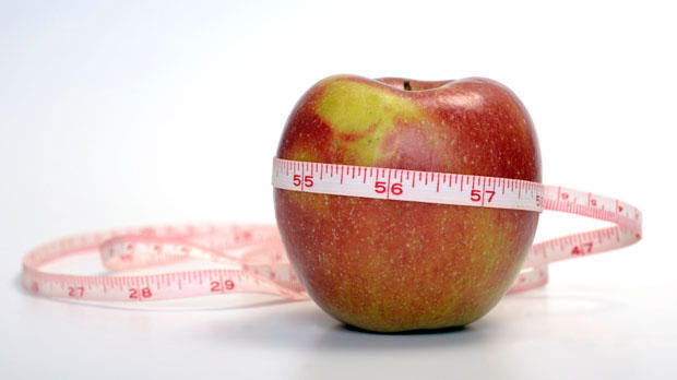 Measuring tape around apple.