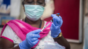 A photograph of a lady holding a vaccine and needle.