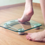 A person stepping onto a set of scales