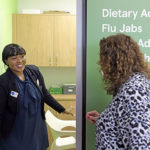 a woman speaking to a female pharmacist outside a consulting room