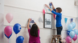 A photograph of two people setting up a CRUK fundraising event