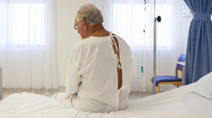 An elderly male patient sat on a hospital bed