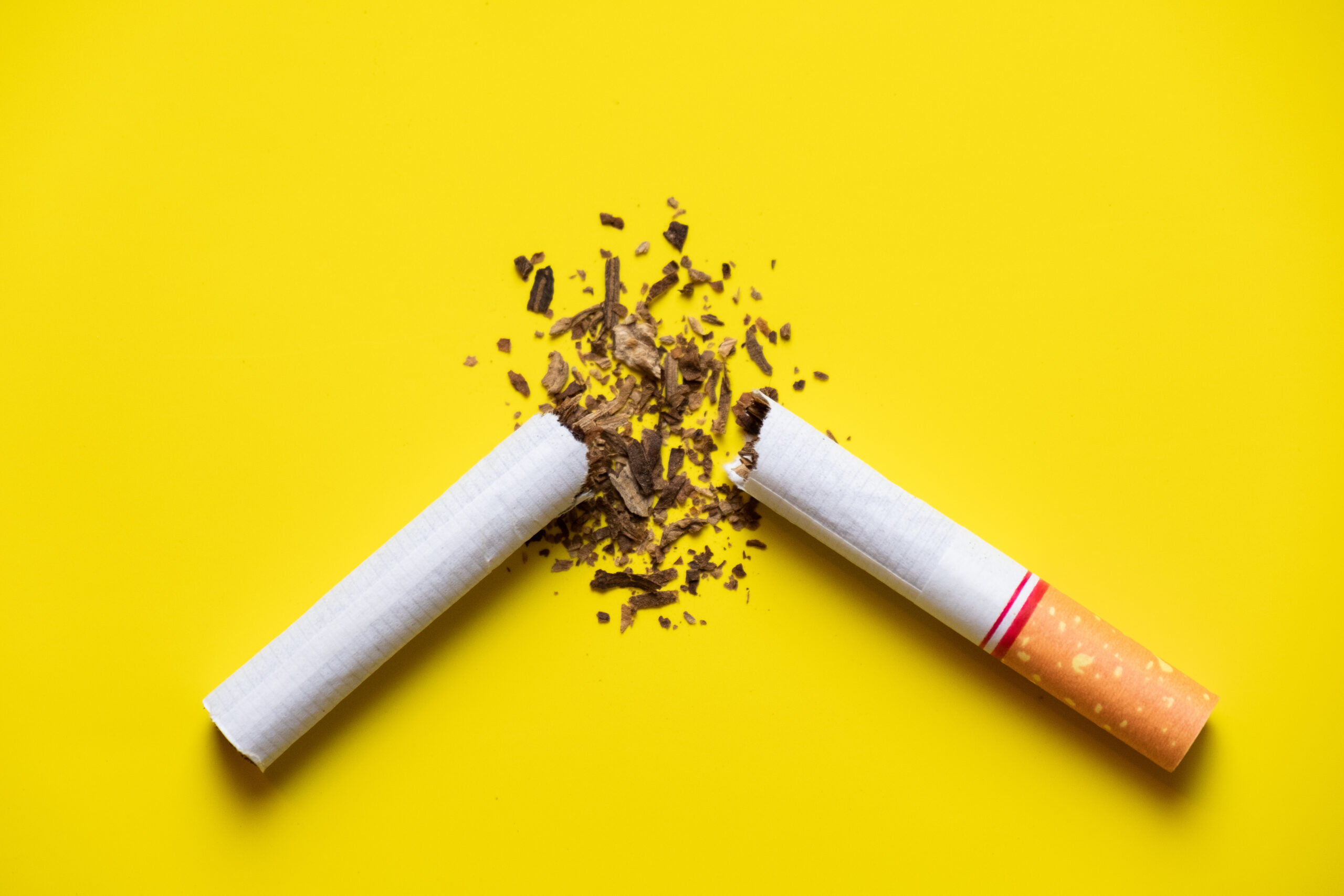 A broken cigarette on a yellow background