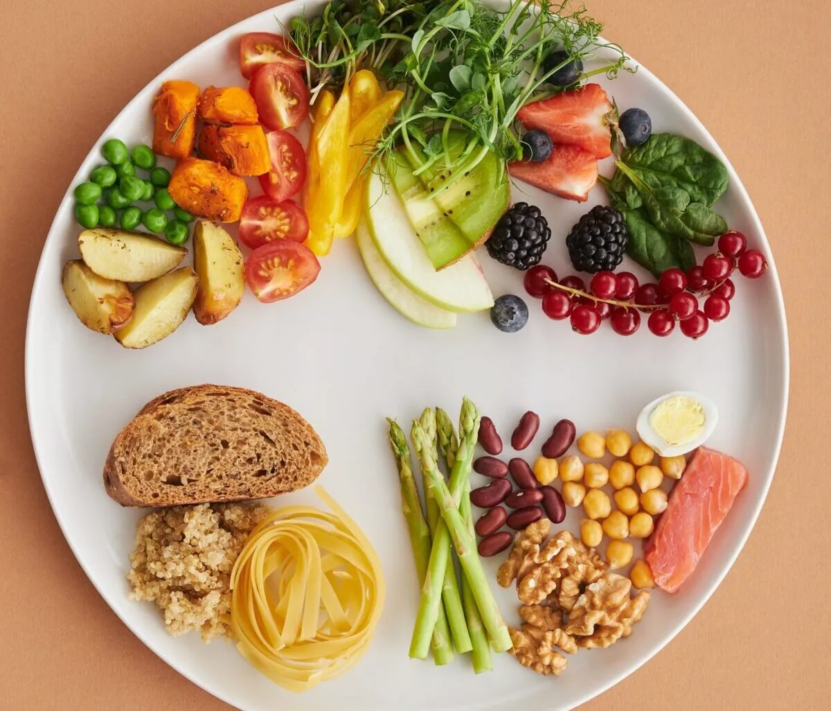 a plate filled with fruit, vegetables, fish and grains