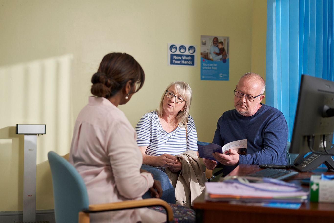 A man and woman speaking to a GP and looking at a leaflet