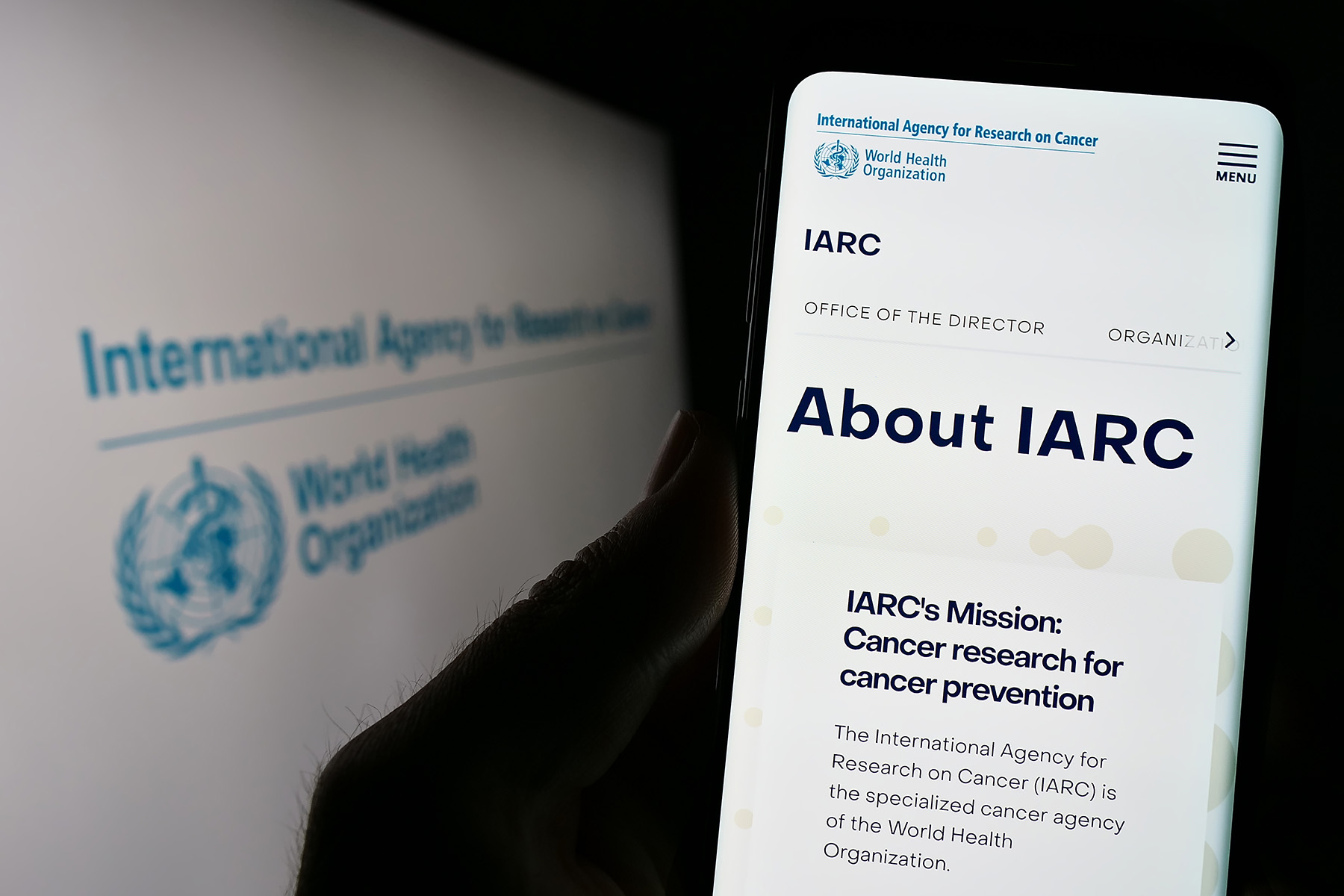 The International Agency for Research on Cancer's (IARC's) website, seen on a phone and a computer.