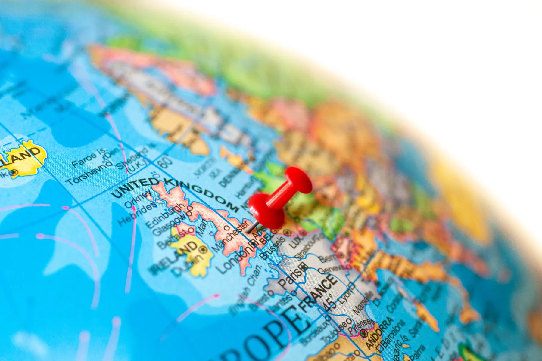A close up of the UK on a globe, with a red pin marking its location