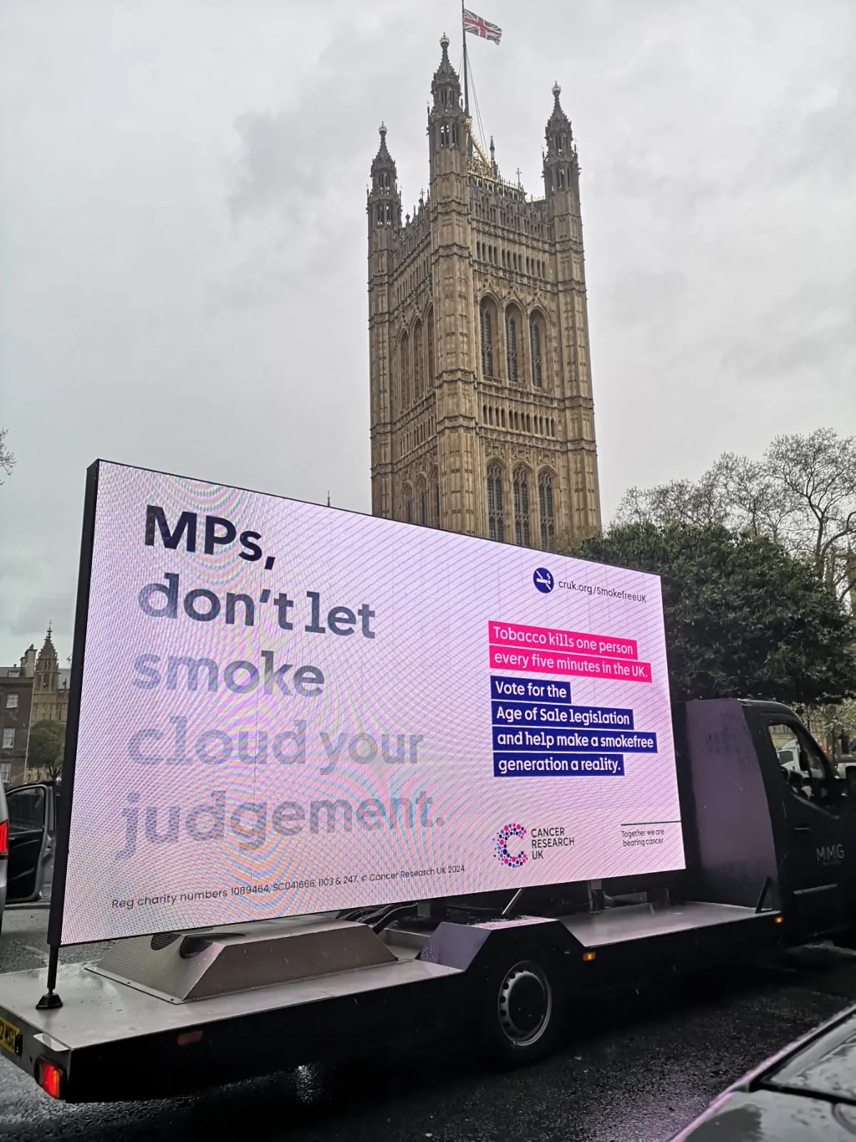 A van holding a digital sign outside the houses of Parliament. The sign reads 'MPs, don't let smoke cloud your judgement.'