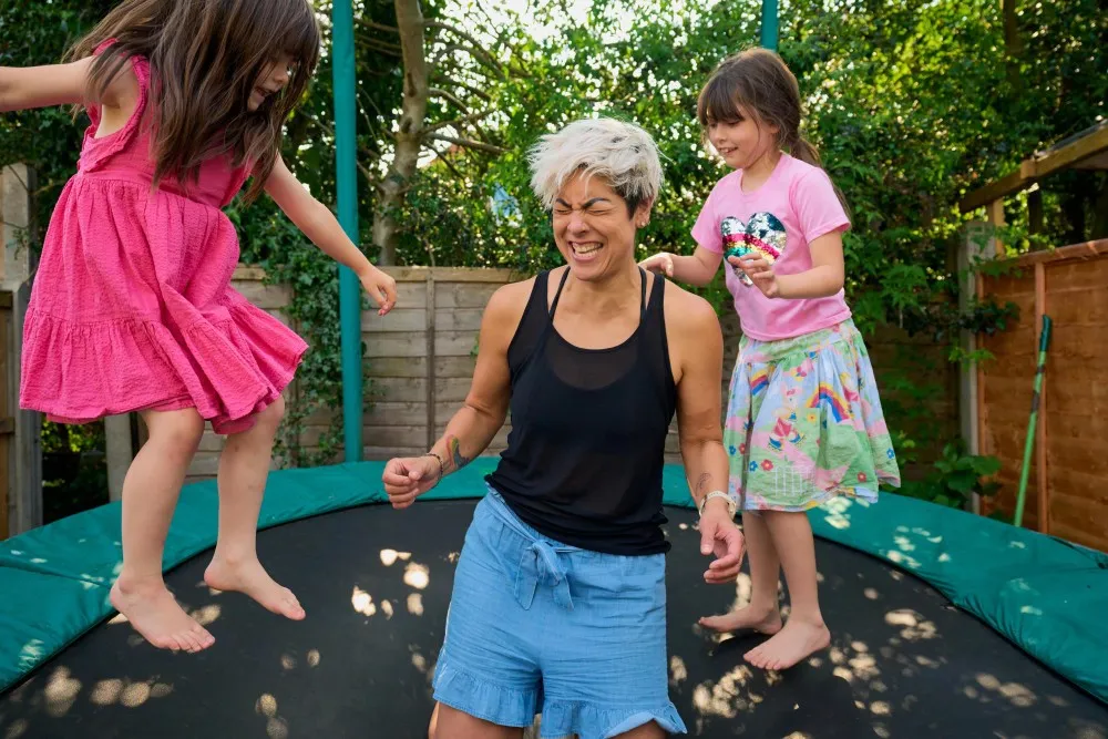 Dr Mei-Ling Lancashire smiling playing on the trampoline with her two daughters