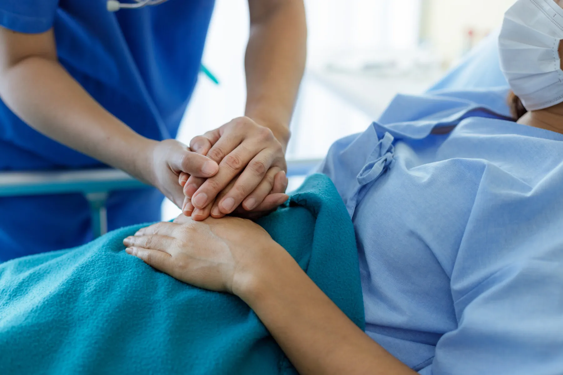 A health professional holding a patient's hand in hospital