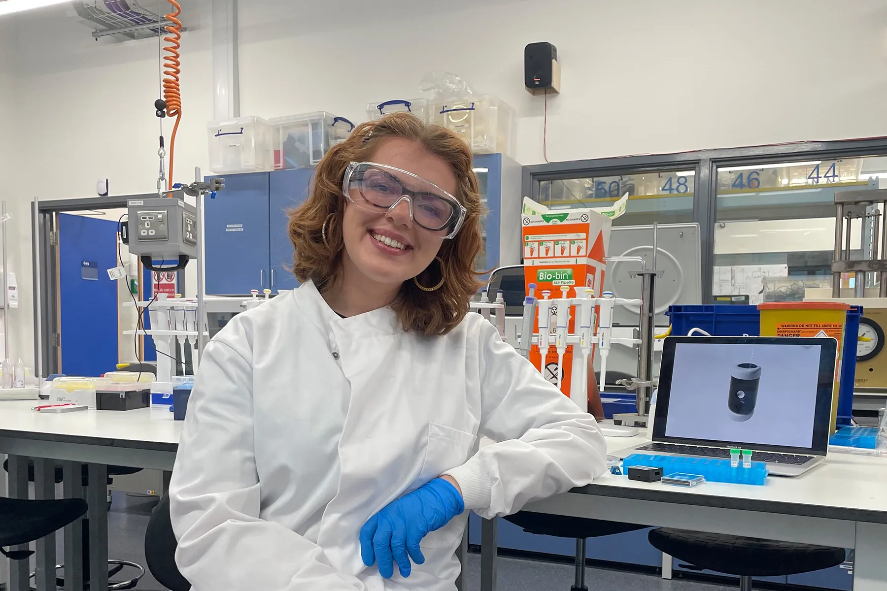 Sânziana Foia in the lab with an image of Papcup, the new HPV test she has designed for cervical screening, on a laptop.