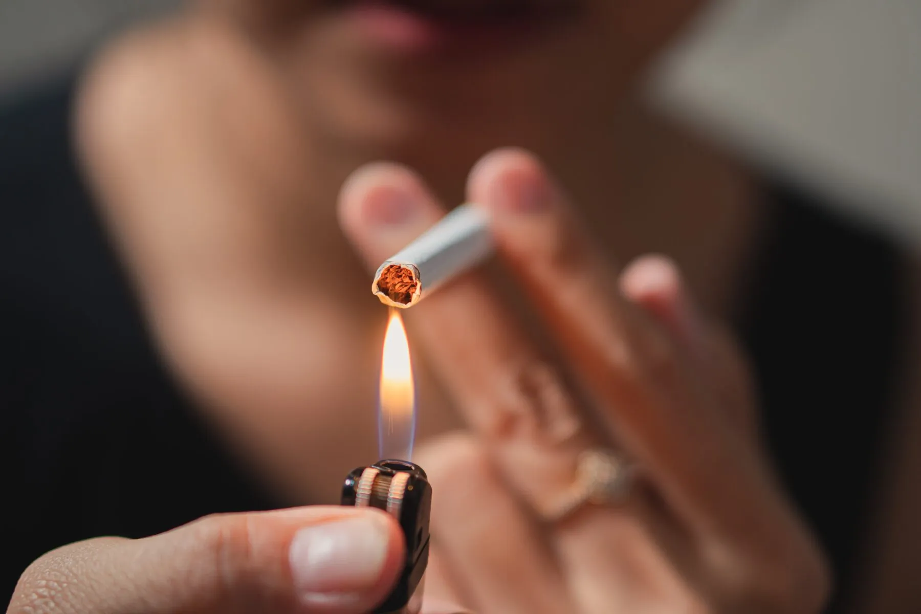 A person lighting a cigarette with a lighter