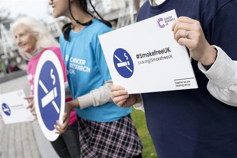 Someone holding a stop smoking sign that says #SmokefreeUK