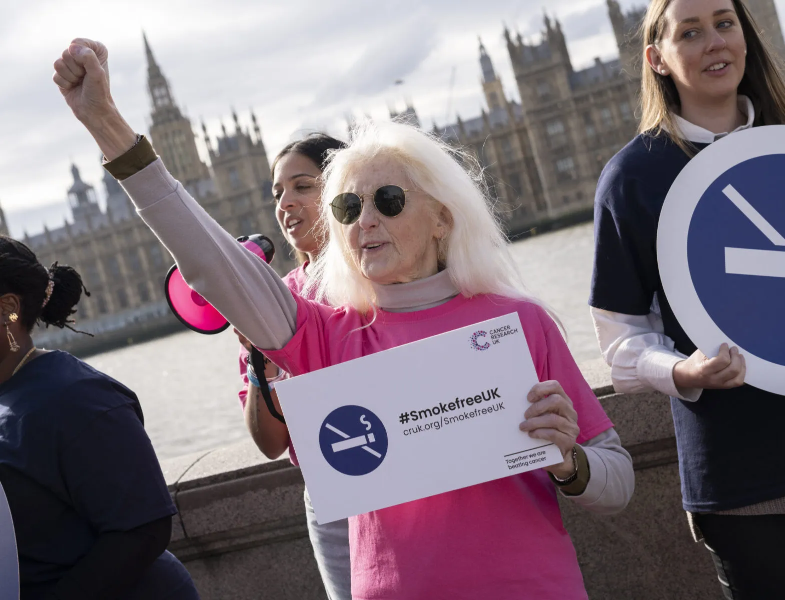 A campaigner holds her arm in the air, holding a sign that says #SmokefreeUK