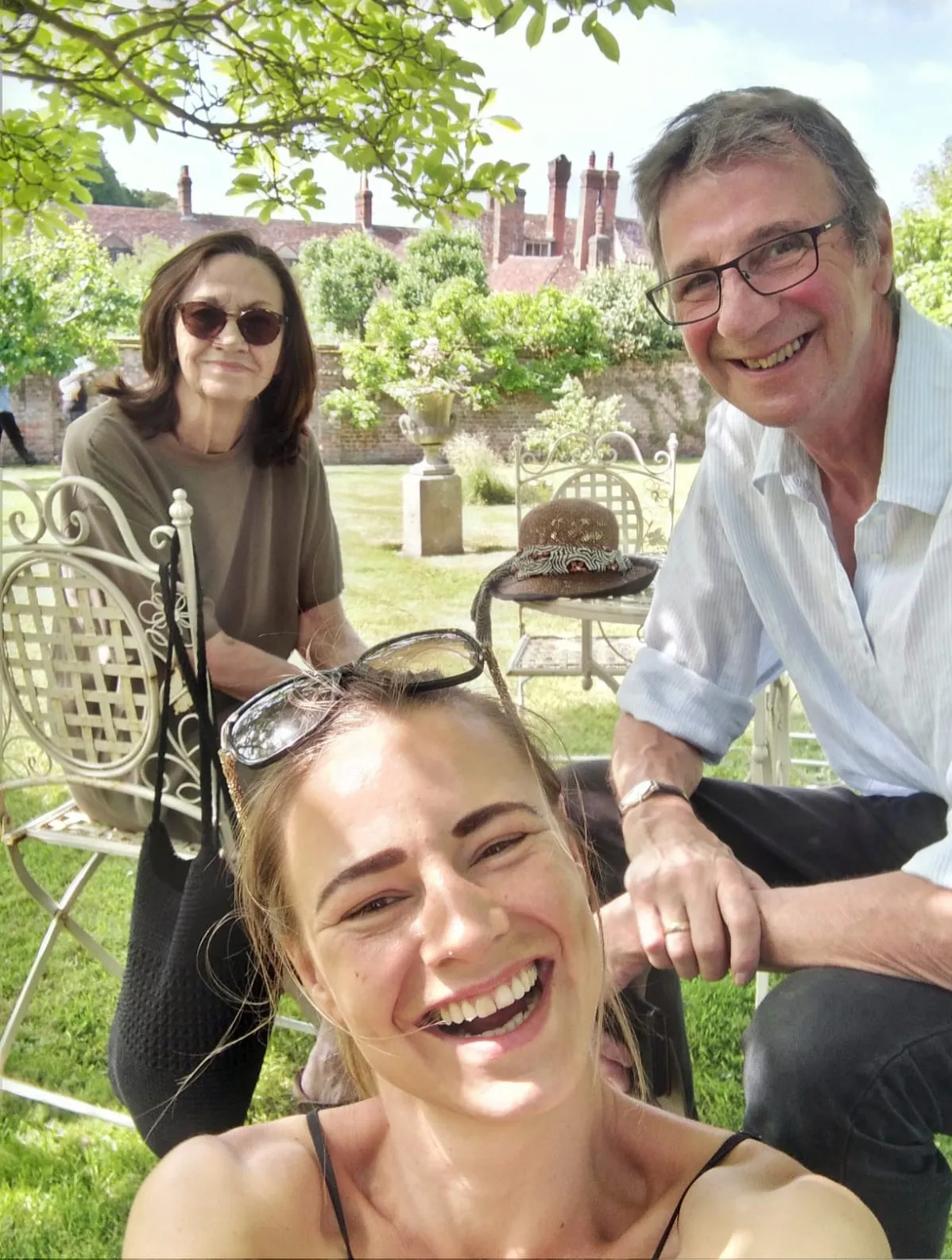 Eileen smiling in a park with her husband and daughter