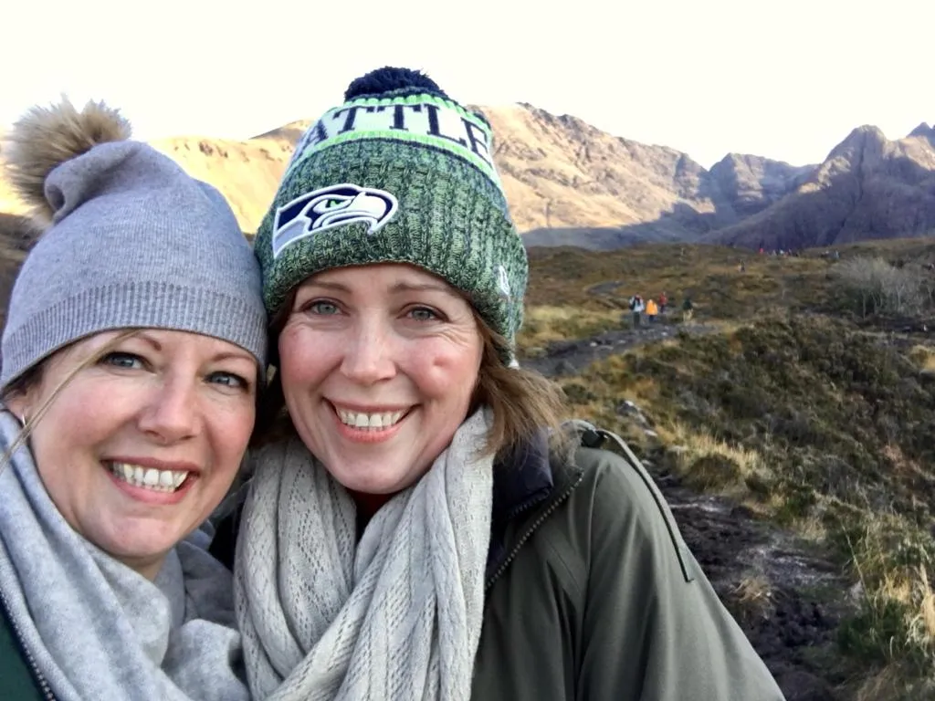 Victoria (left) and Rebecca Fletcher (right) smiling in front of a green hill landscape