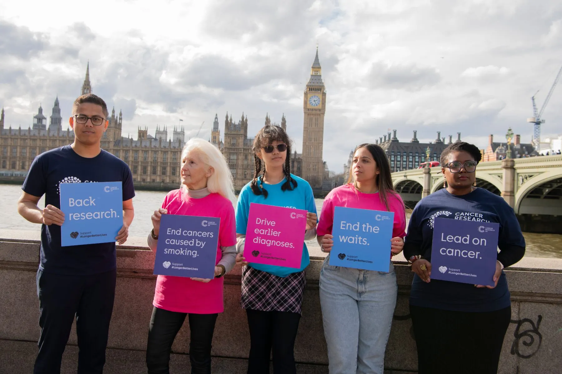 5 people holding signs across the river from Westminster