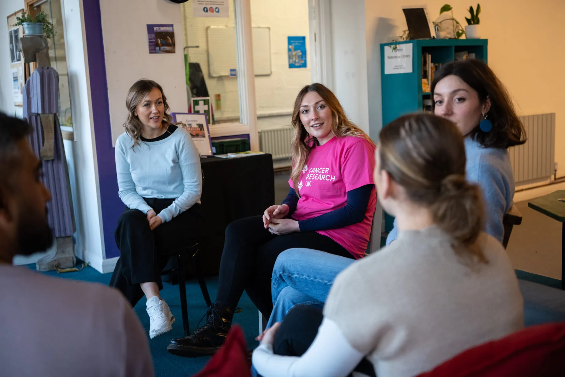 A group of volunteers sitting on chairs and talking to each other