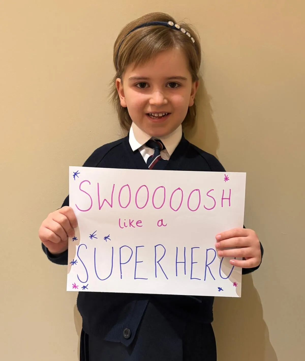 Fearne stands holding a sign that says 'Swooooosh like a superhero'