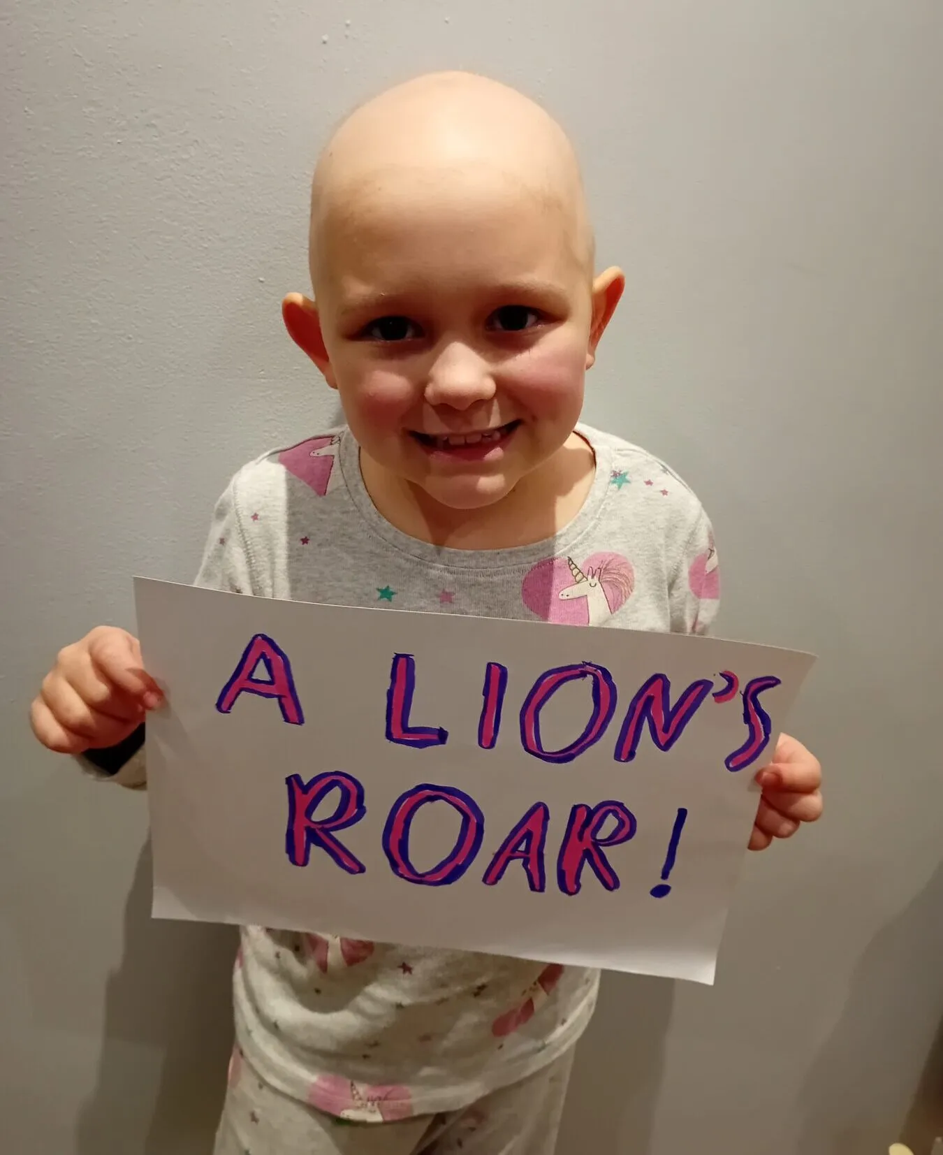 Lily, a young girl, holding a sign that says 'A lion's roar!'