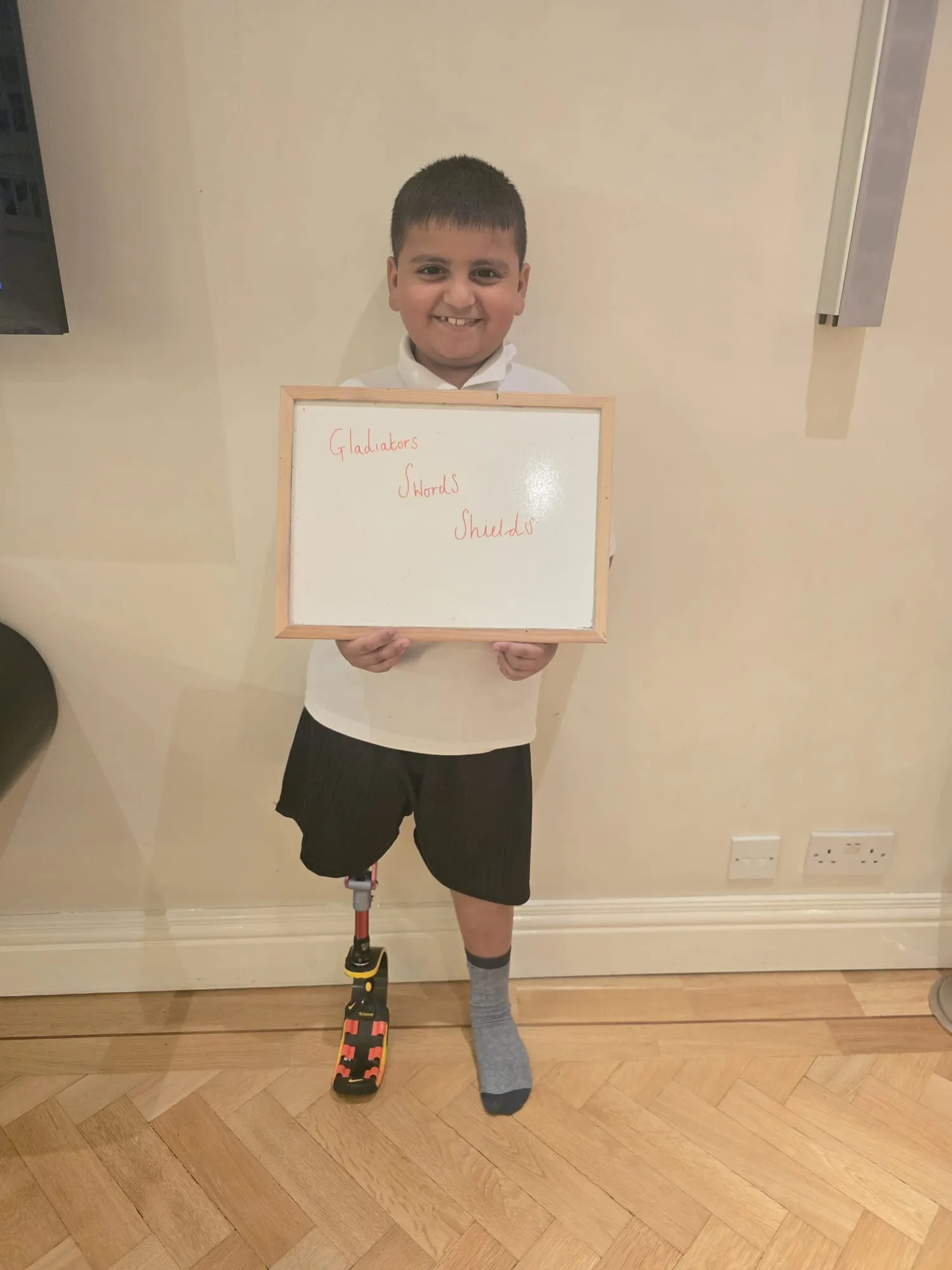 Saif, a young boy with an artificial limb holding a sign that says 'gladiators, swords, shields'