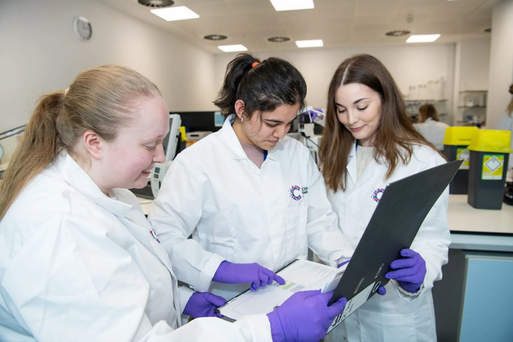 A group of three Cancer Research UK scientists Group of researchers looking at a data file in a lab