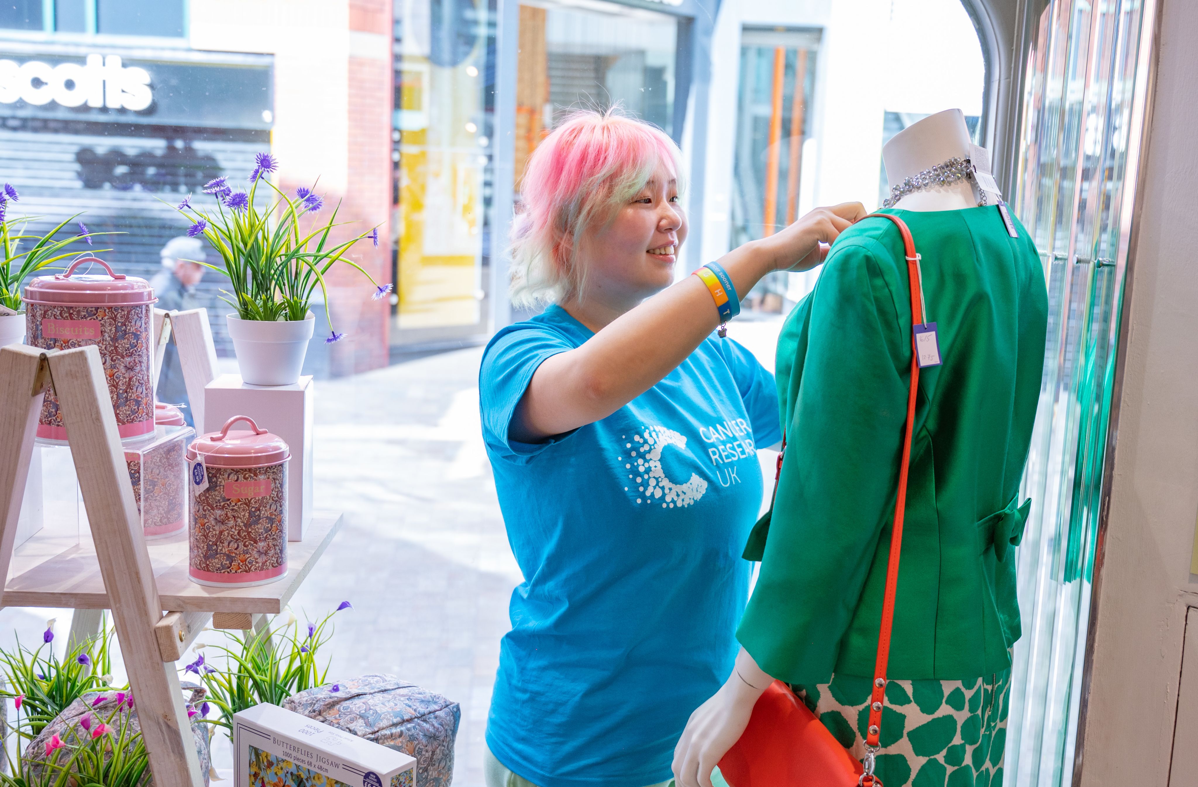 A shop assistant fitting clothes on a mannequin 