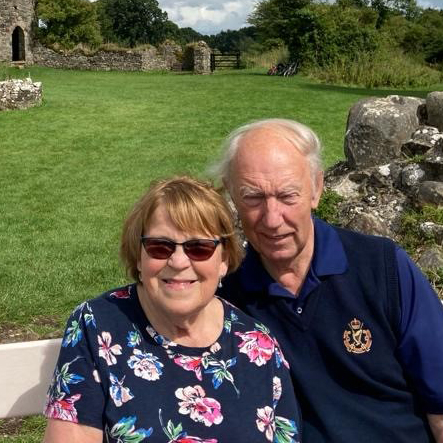 A picture of Archie and his wife sitting on a bench outside