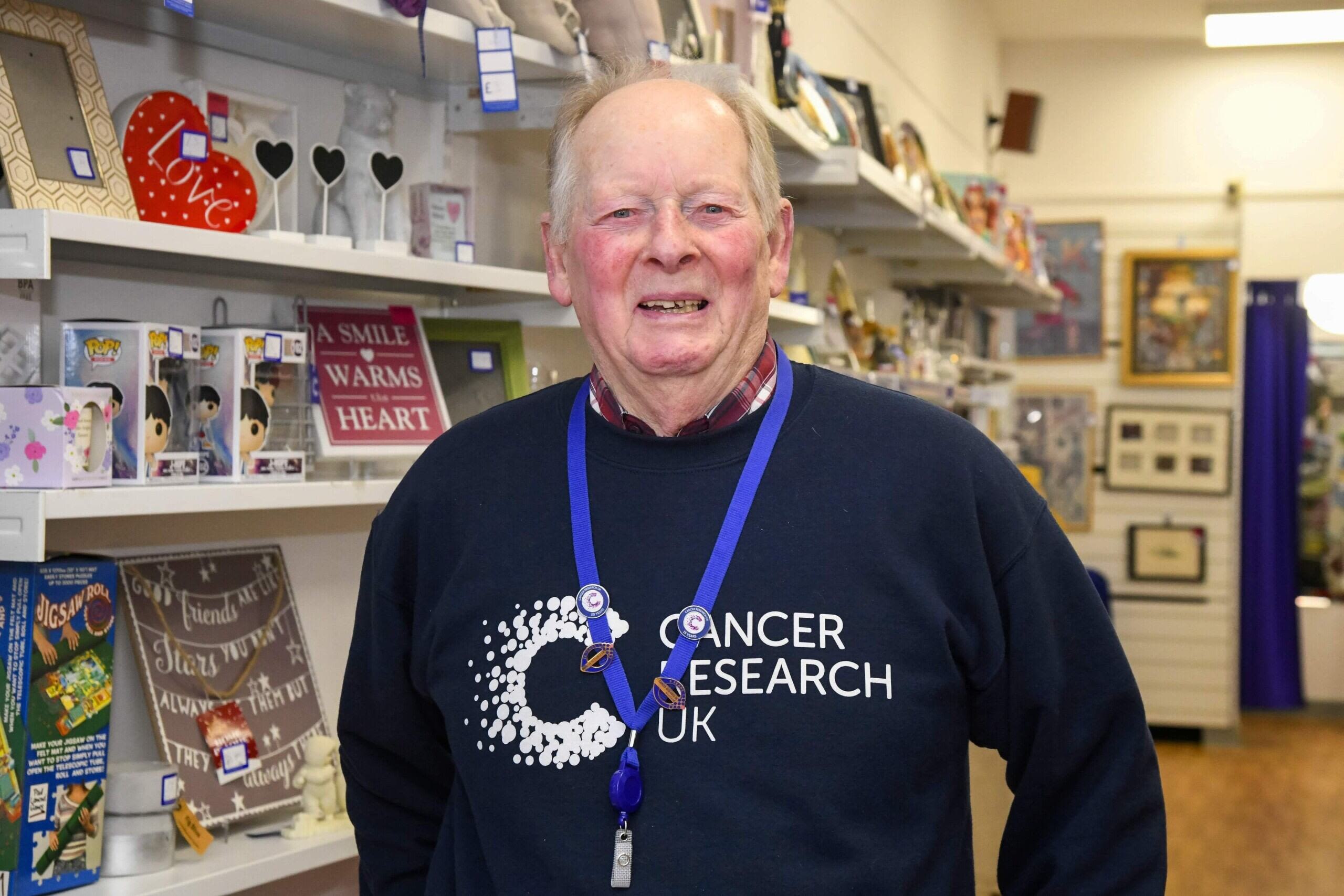 A man (John) standing in a shop wearing a Cancer Research UK branded jumper