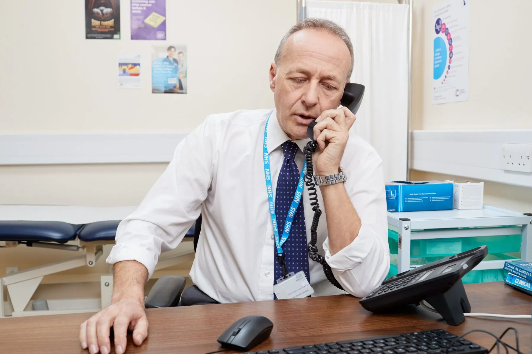 This photo shows a GP on the phone in his office.