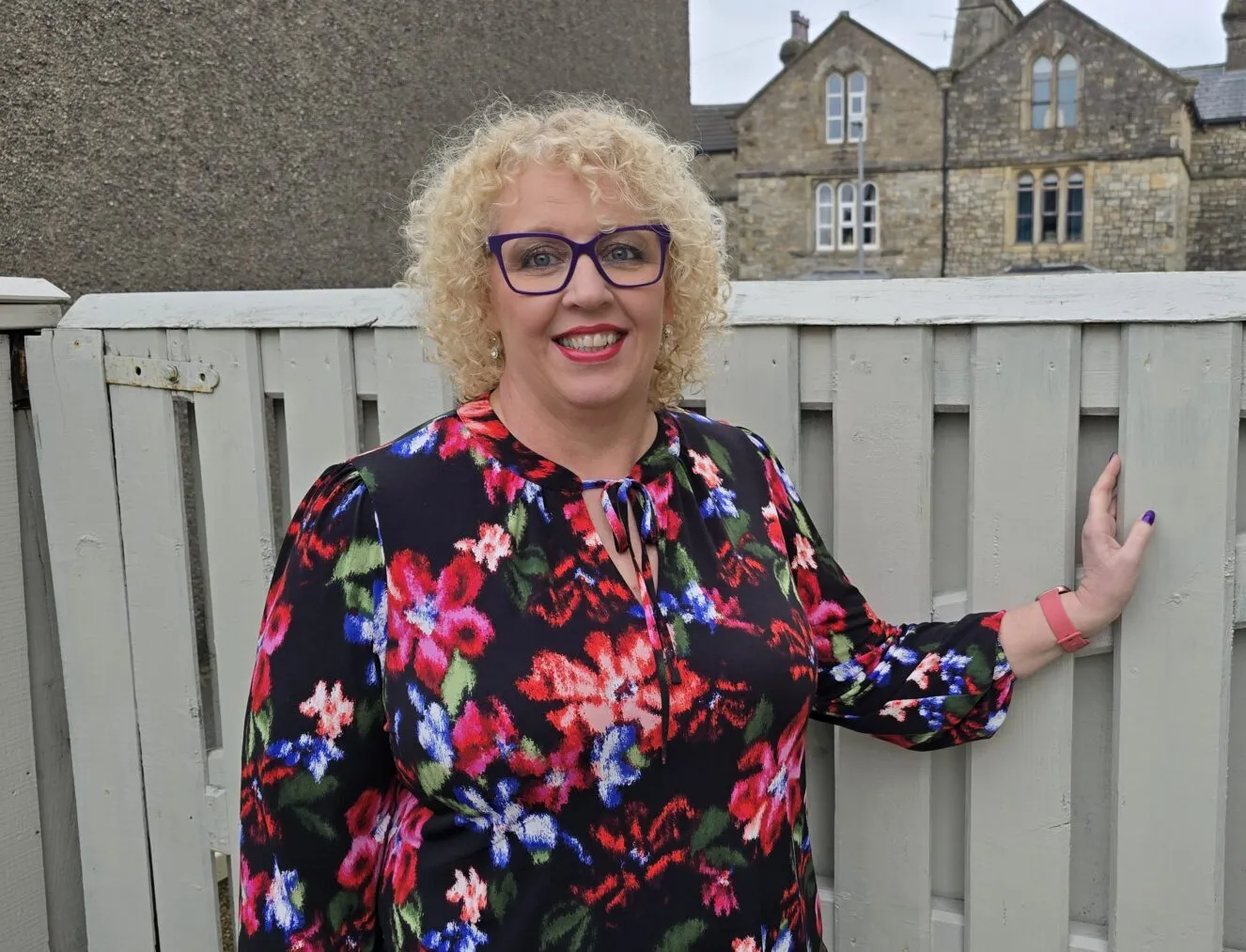 A picture of Karen standing by a garden fence