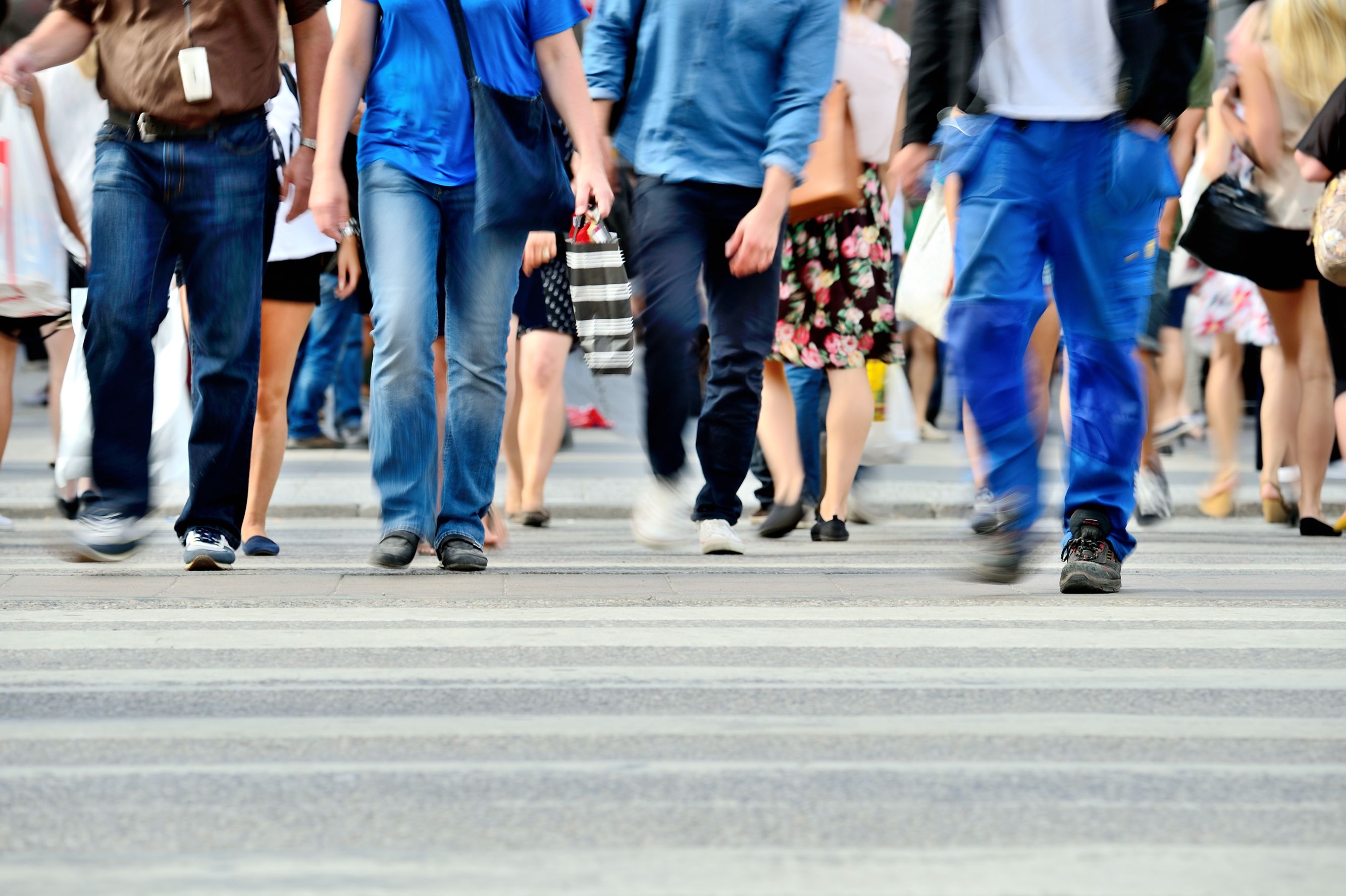 A picture of people's legs walking across a road