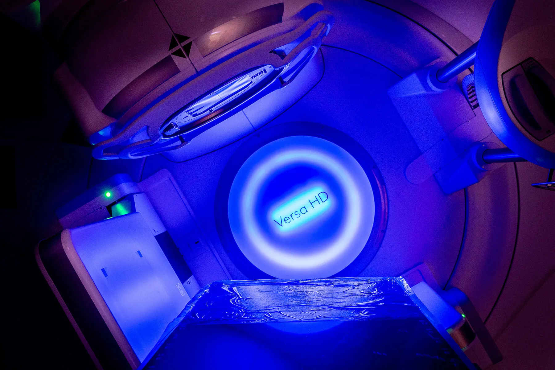 An image of a radiotherapy machine. Its lights are glowing blue.