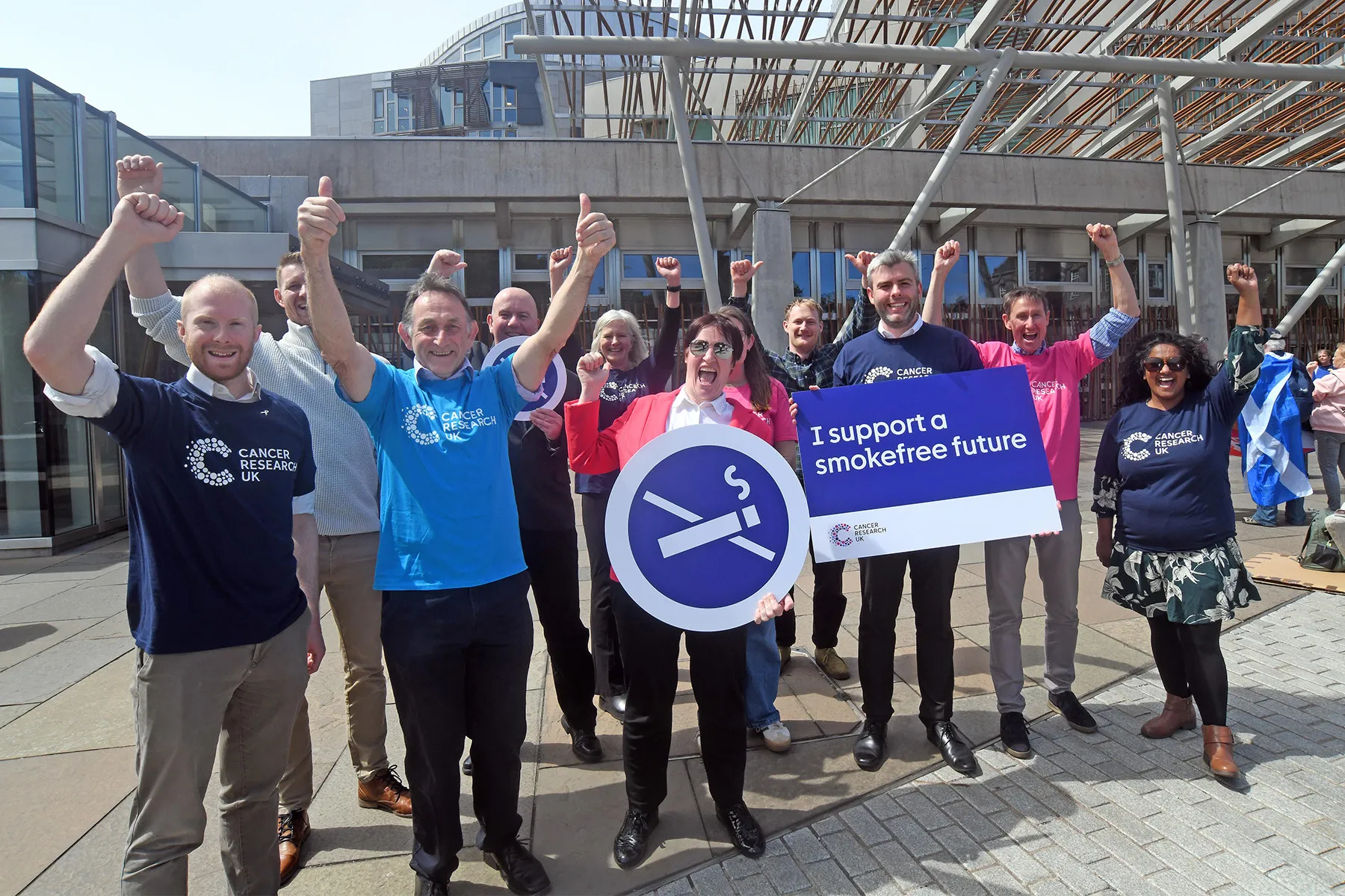 A group of Cancer Research UK campaigners celebrating with signs saying 'I support a smokefree future'