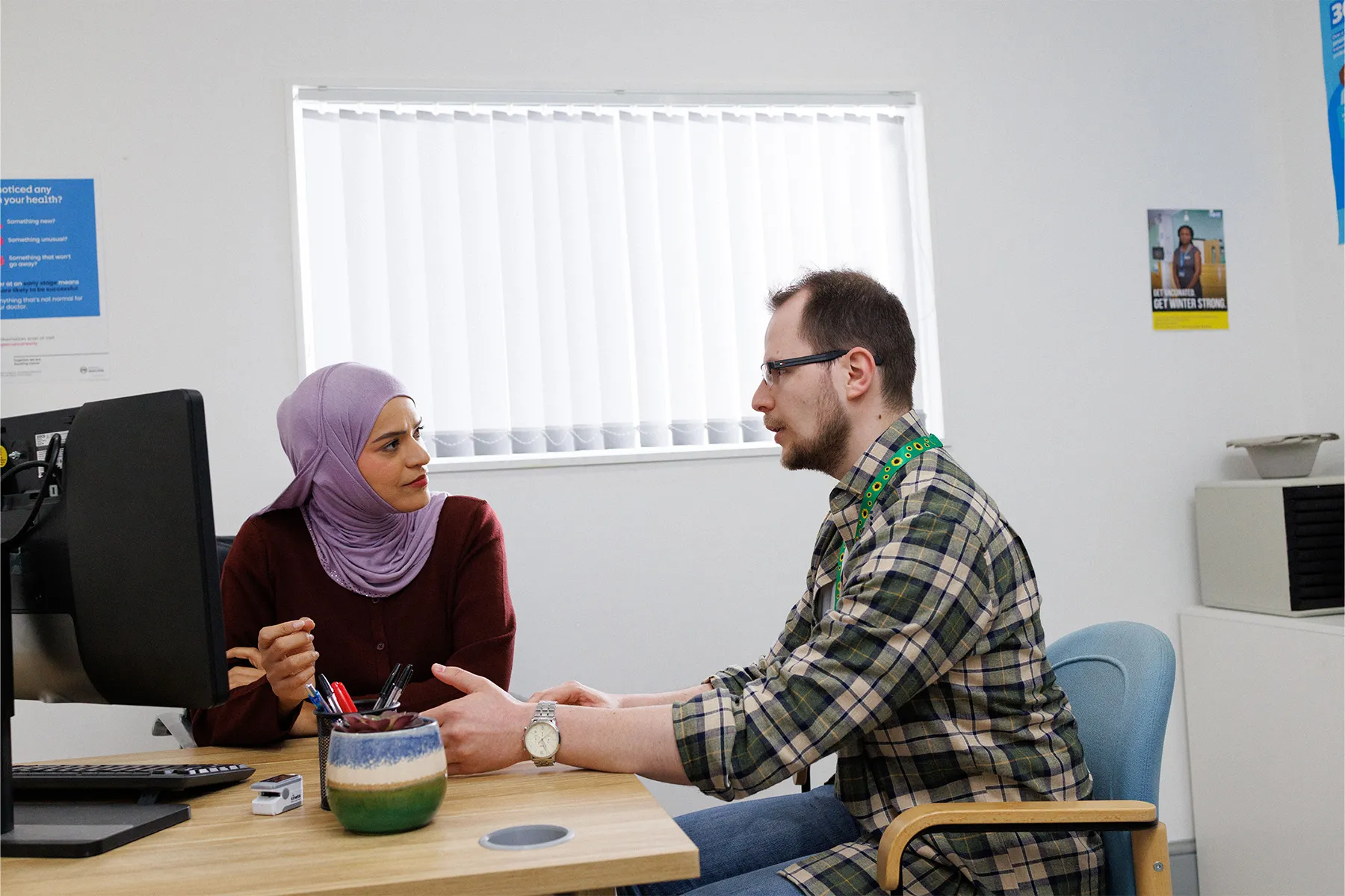 A doctor sat behind her desk talking to a patient.
