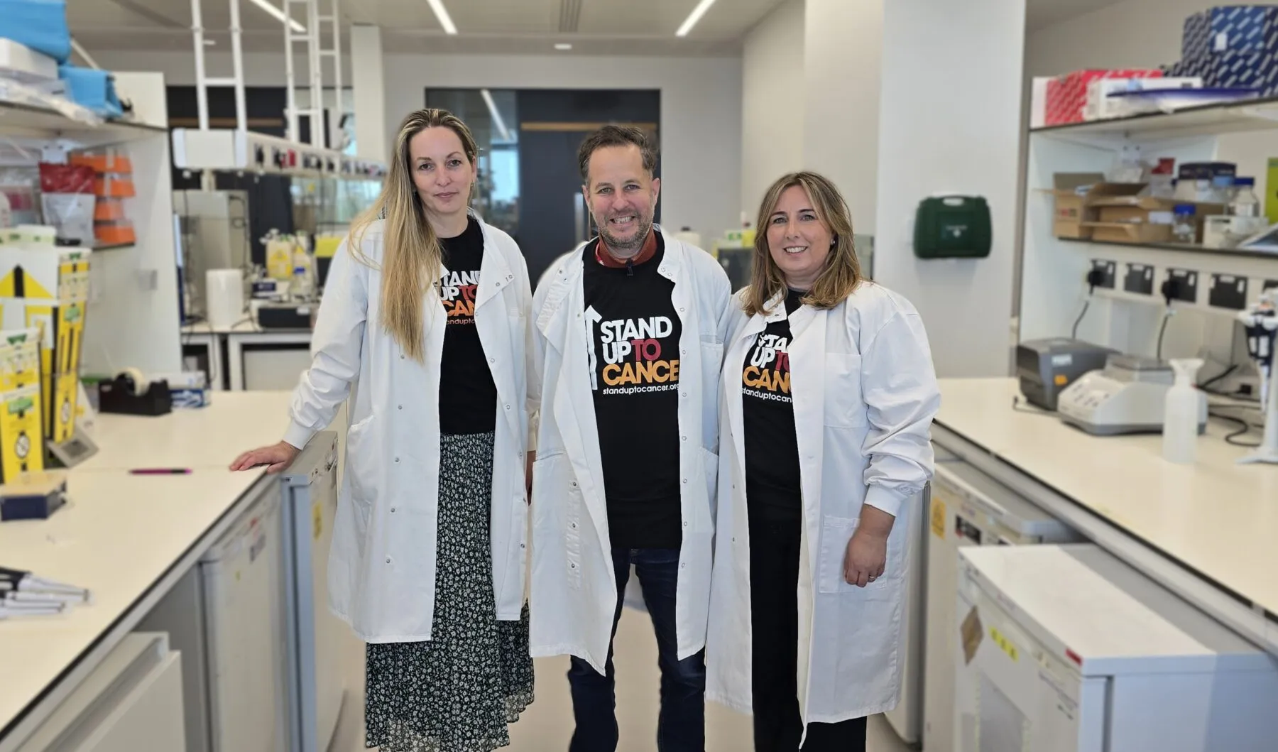 Three people in a laboratory in lab coats.
