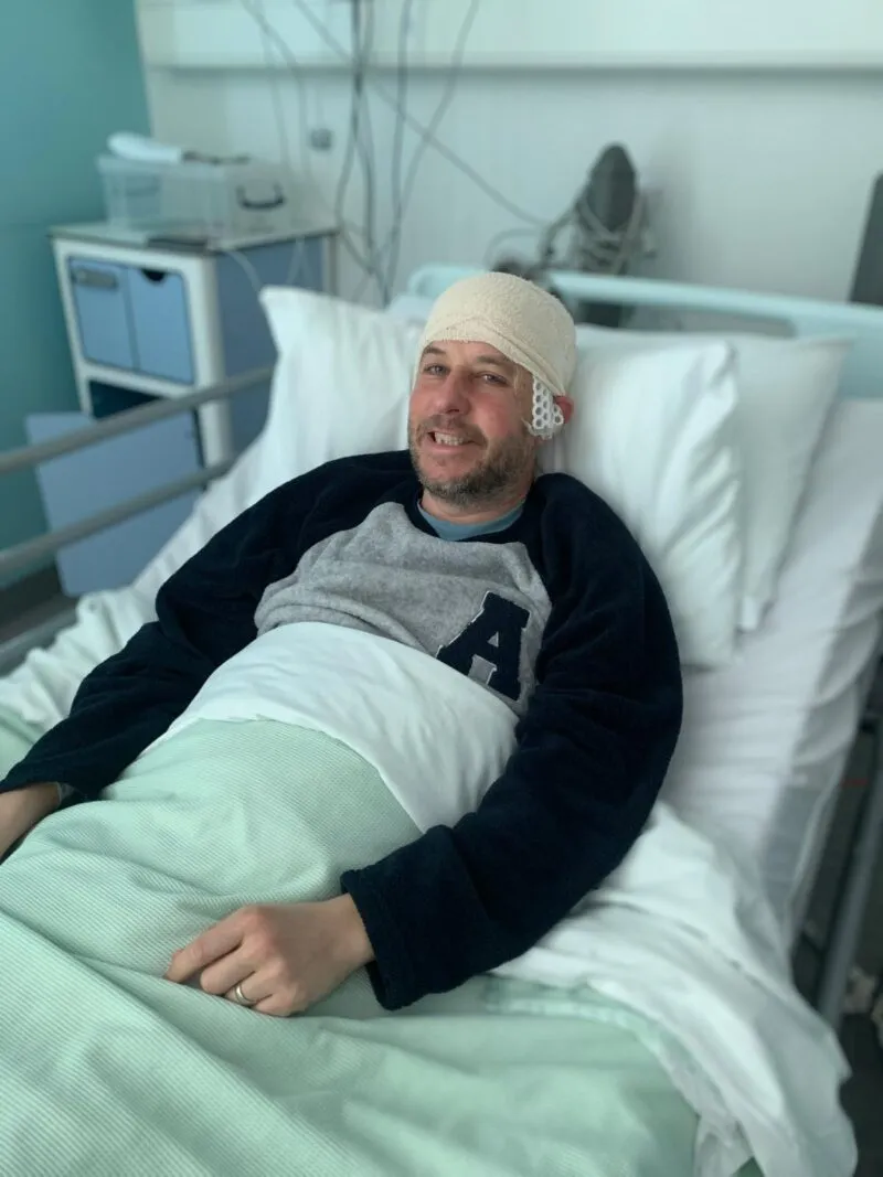 Man in hospital with a bandage on his head.