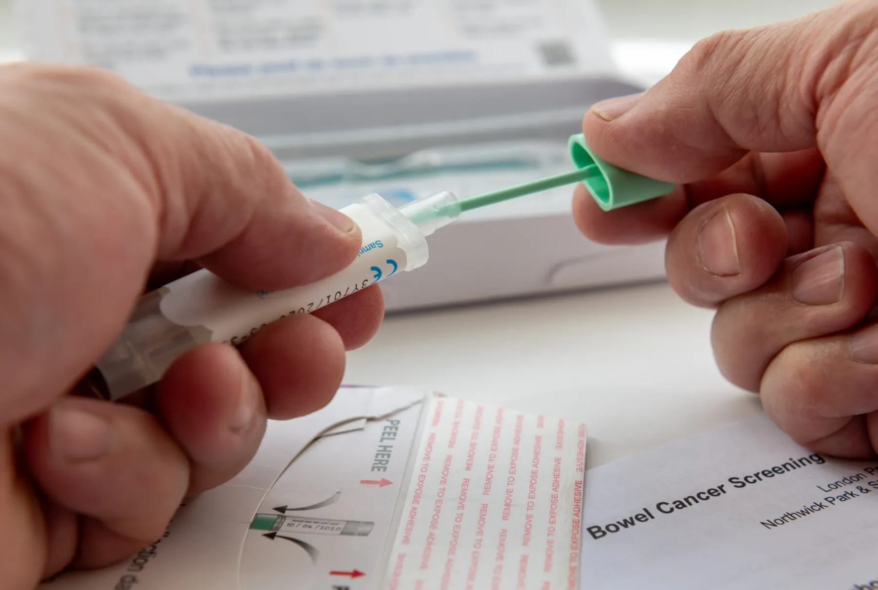 A close up shot of a person putting the bowel cancer test sample in the sample holder to send off by mail for testing.
