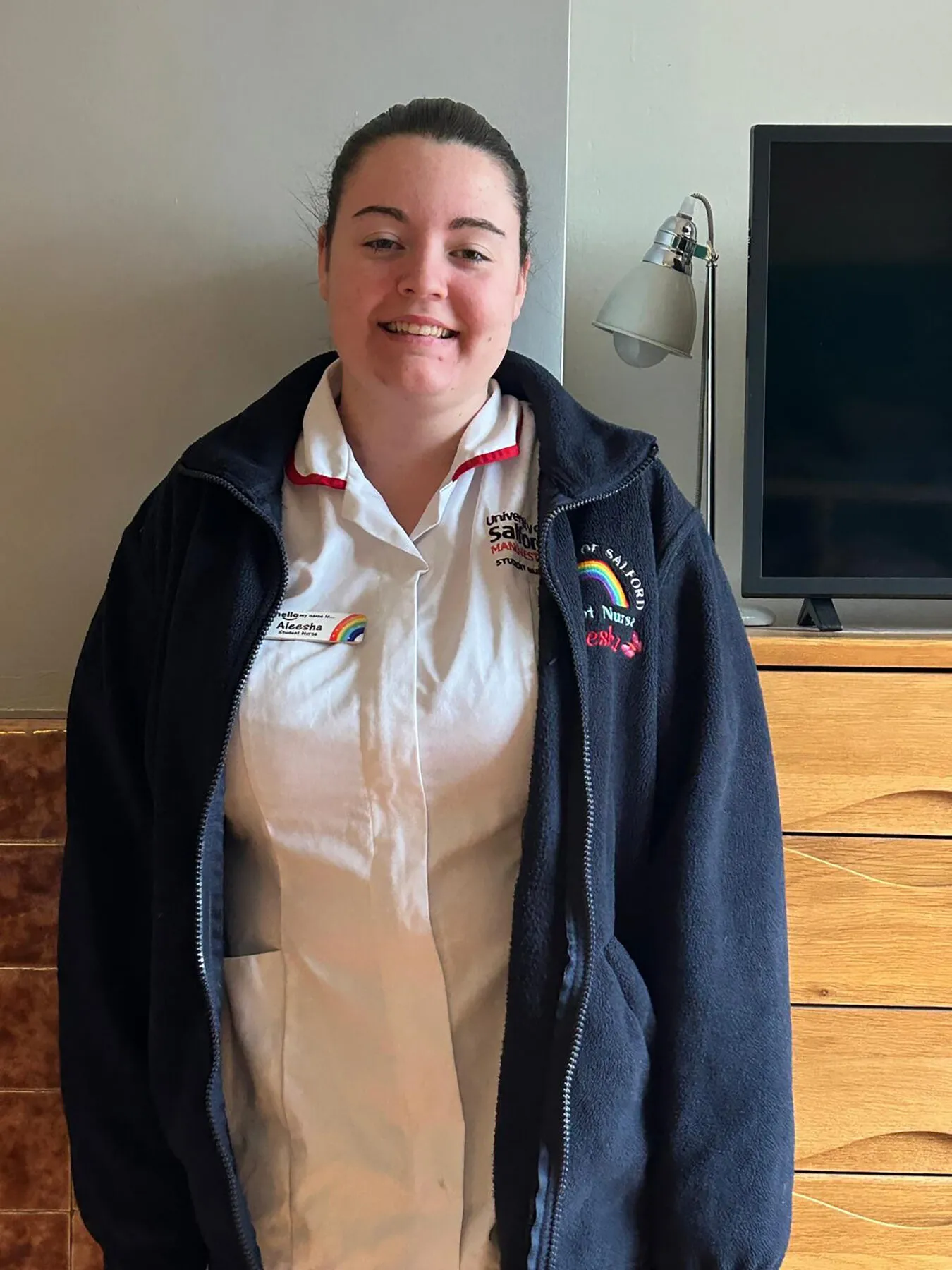 Aleesha-Marie smiling at the camera in her nurse's uniform.
