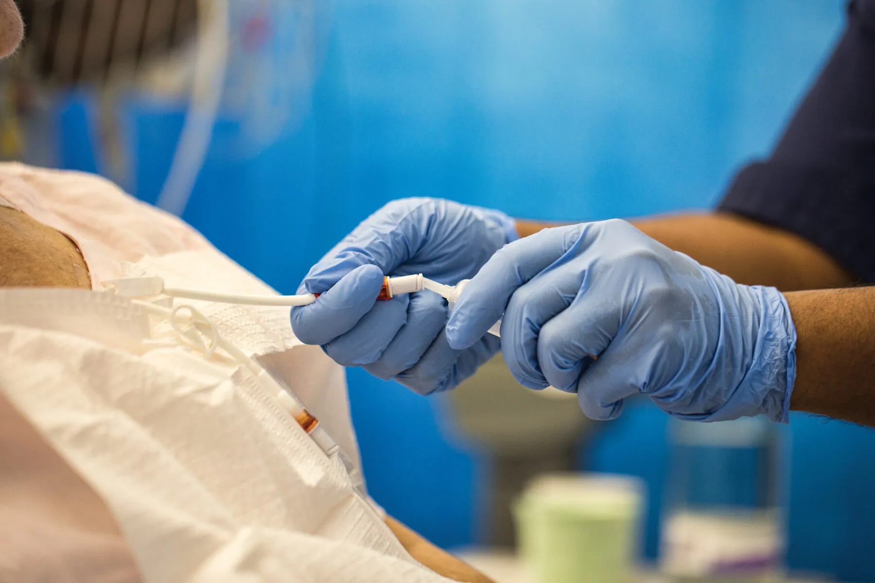 clinician wearing giving treatment via tube to patient wearing a white hospital gown