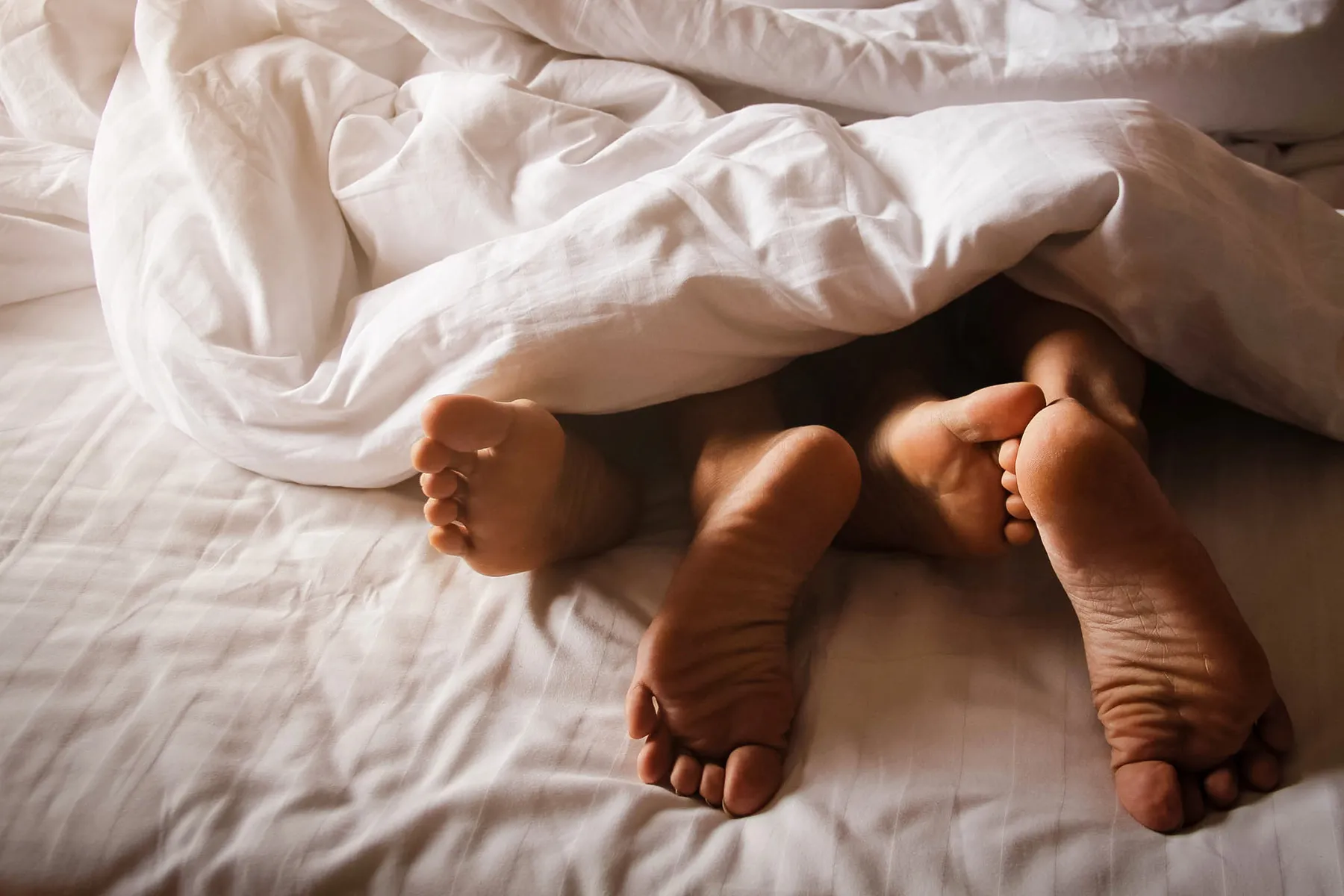 Two people's feet in bed.