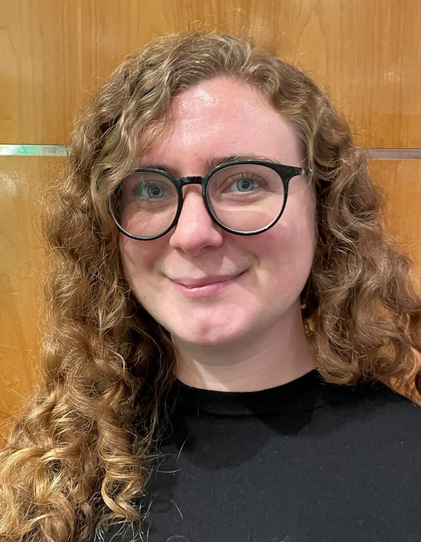 headshot of a lady with glasses and curly hair